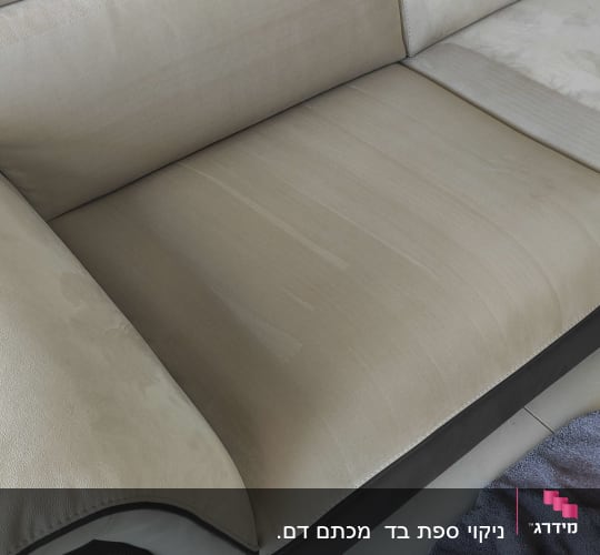 ספה בהירה עם מגבת כחולה על הרצפה